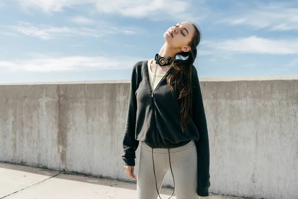 Atletica giovane ragazza in eleganti vestiti neri riscaldamento prima della formazione sotto il cielo blu — Foto Stock