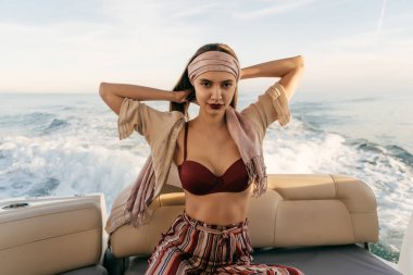 bir lüks şık kız moda yaz giysileri beyaz bir yatta oturur, deniz yolculuğu sahiptir