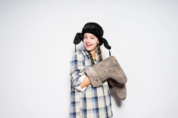 Laughing young russian girl in warm fur hat holds winter felt boots in hands and smiles — Stock Photo, Image