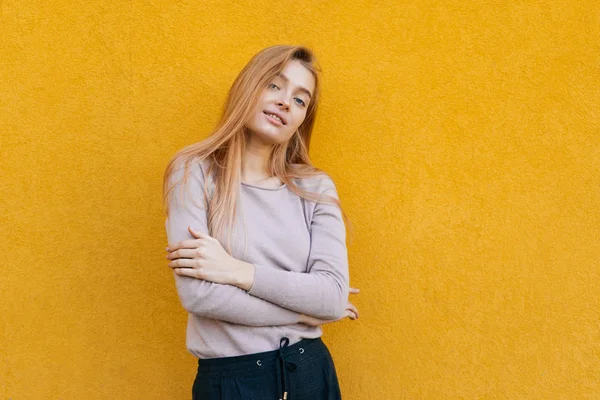 Hermosa chica confiada modelo rubio posando sobre un fondo de pared naranja, estilo de calle y moda — Foto de Stock