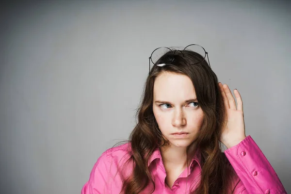 Insatisfeito jovem trabalhador de escritório mulher em uma camisa rosa ouvindo algo — Fotografia de Stock