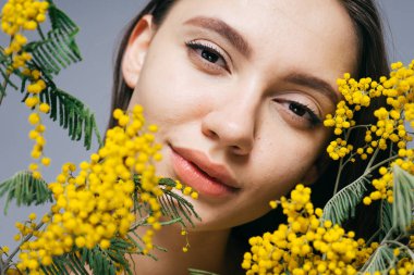 güzel kokulu sarı Mimoza holding, poz ve kameraya bakarak sevimli çekici kız