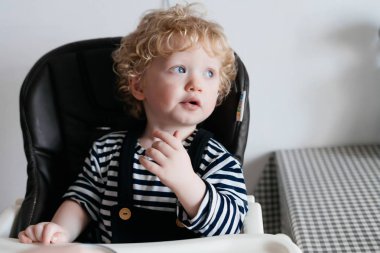 Mutfakta, oturma ve uzağa arıyorsunuz mavi gözlü kıvırcık küçük bebeğim