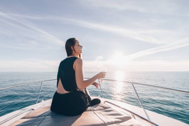 siyah şık elbiseleri lüks bir genç kız aittir ve onun yatta rahatlatır, şampanya içiyor