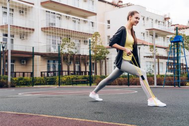 açık spor alanı üzerinde bacak egzersizleri yapıyor ince atletik kız