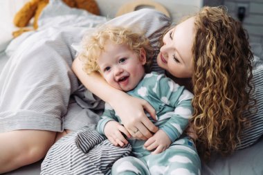 eğleniyor, sarılma onun genç çocuk çocuk oğlu ile oynarken kıvırcık Genç Anne