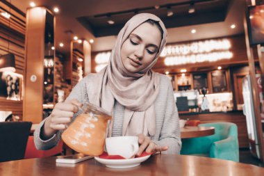 iyi bir Müslüman kız başında başörtüsü ile rahat bir mkafe akşam, sıcak çay içer
