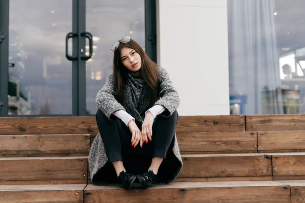 Красива молода міська брюнетка дівчина сидить на сходах на відкритому повітрі, відпочиває — стокове фото