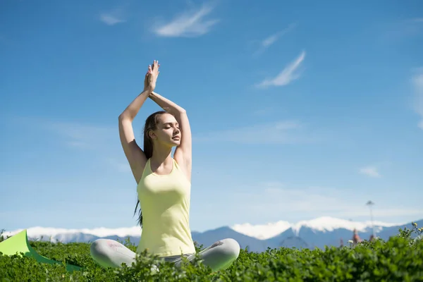 Štíhlá dívka medituje a uvolňuje v parku na slunci, dělá jógu — Stock fotografie