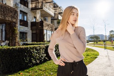 Açık havada güneş altında poz Modern giyimleri şık genç sarışın model kız