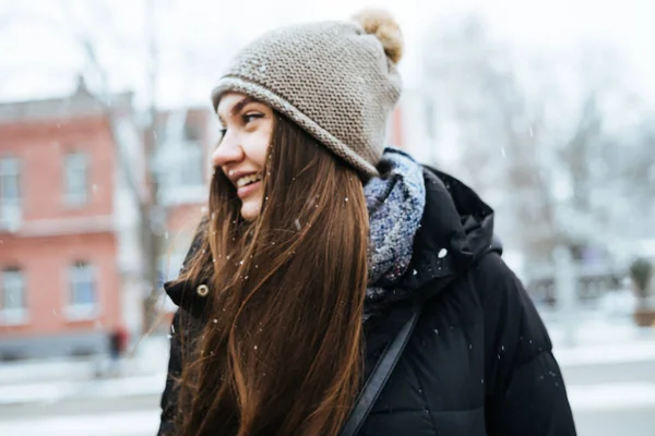 Śmiejąc się długo haired Dziewczyna w kapeluszu spacery po ulicach miasta, i szczyci się zimą — Zdjęcie stockowe