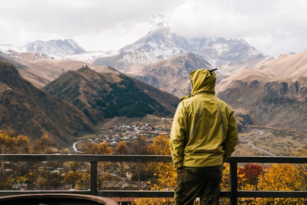 A male traveler in a warm jacket enjoys the mountain scenery and clean air — Stock Photo, Image