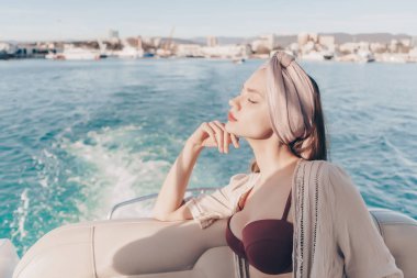bir başörtüsü başında çekici genç kadın sahiptir tatile denizde, güneşin gözleri kapalı