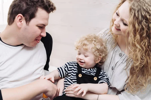 Amigable familia feliz, joven mamá y papá jugando con su pequeño hijo y riendo — Foto de Stock