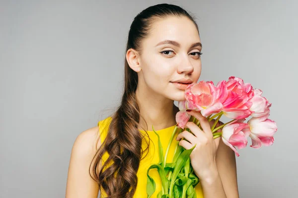 Encantadora menina desfrutando da primavera segurando um buquê de flores rosa perfumadas — Fotografia de Stock