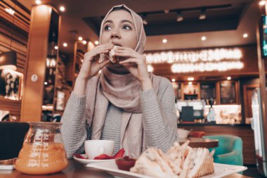 bir restoranda lezzetli yemek yeme başında başörtüsü ile Şirin genç Arap kız