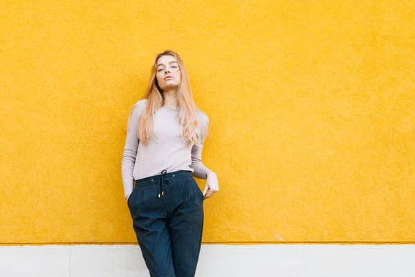 Уверенная молодая блондинка модель девушка позирует на фоне желтой стены, уличный стиль и мода — стоковое фото