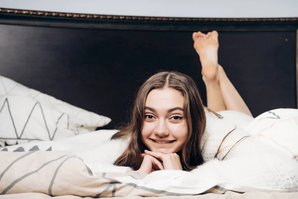 Gyönyörű szép lány fekszik az ágyban reggel, mosolyog, és nem akar-hoz kelj fel — Stock Fotó