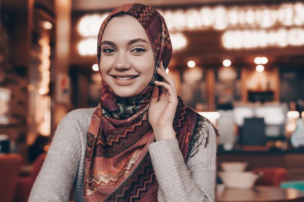 Souriante fille arabe dans le hijab se trouve dans le café, attendant sa nourriture et souriant — Photo