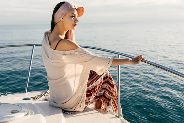 An attractive young girl in summer stylish clothes rests on her yacht, sails on the Caribbean sea — Stock Photo, Image