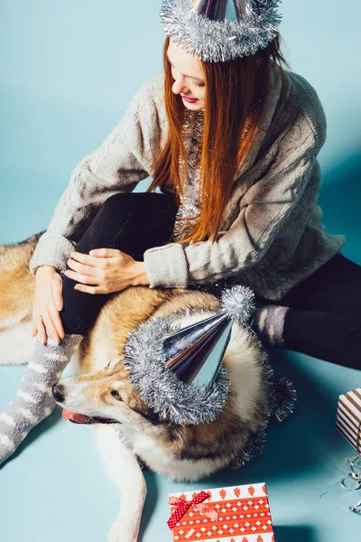 Belle fille aux cheveux roux dans un chapeau célèbre la nouvelle année et Noël avec son gros chien — Photo