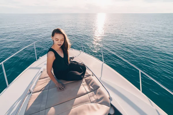 Стильная молодая девушка в черной летней одежде сидит в лодке, плавает по Карибскому морю на острова — стоковое фото