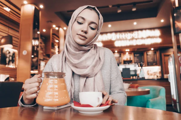 Egy vonzó Arab lány fején fejkendőt ebédel, egy hangulatos étterem, tea italok — Stock Fotó