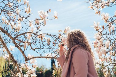 zarif kıvırcık kadının güneş ışınlarının bir parkta çiçek açan bir Manolya kokusu