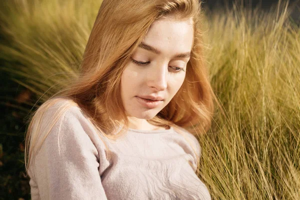 Beautiful young blond girl lies in a field in the sun, posing and resting — Stock Photo, Image