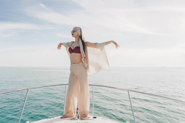 A luxurious young woman in stylish summer clothes posing on her white boat, sailing to the island — Stock Photo, Image