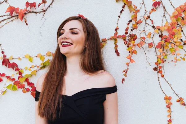 Lujosa chica de pelo largo riendo, descansando y posando contra la pared en su jardín — Foto de Stock