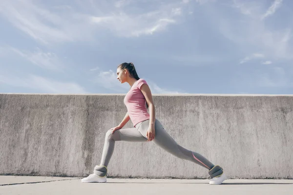Een sportief slank meisje kneedt en strekt zich uit voor een outdoor training — Stockfoto