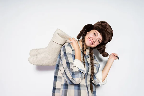 Laughing Russian girl in a fur hat holds gray winter boots — Stock Photo, Image