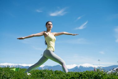 Sakin, ince kız parkta güneş yoga yapan, derin derin düşünür ve rahatlatır