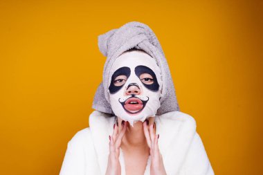 beyaz bir sabahlık ve başında bir havlu ile garip bir genç kız kendini sonra bir panda yüz nemlendirici maske yüzünde görünüyor