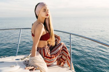 çekici bir şık kız moda pantolon içinde güneşin bir teknede oturur, rahatlatır ve rahatlatır