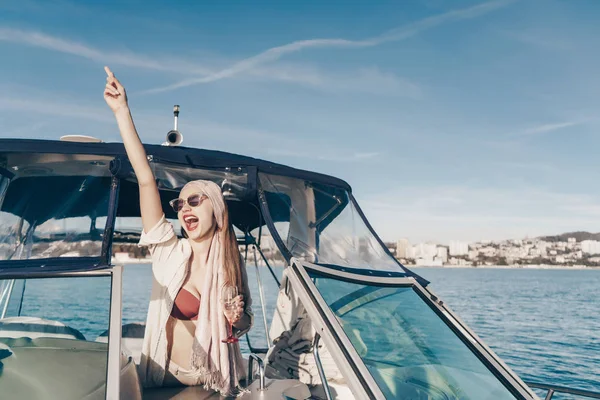 Den glädjefull skrattande flickan åtnjuter ett rikt liv på sin yacht, seglar Karibiska havet och dricker champagne — Stockfoto