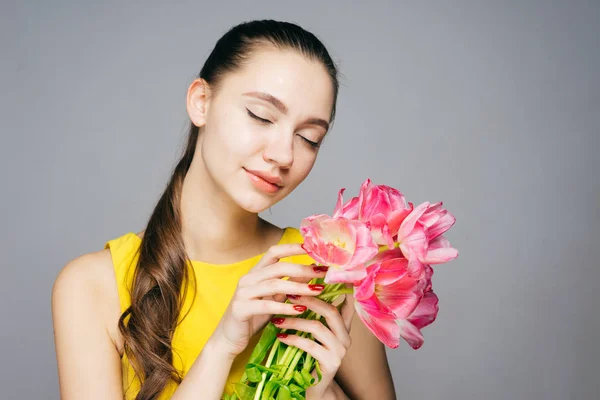 Mooie jonge vrouw genieten van het voorjaar, roze bloemen, houden haar ogen sluiten — Stockfoto