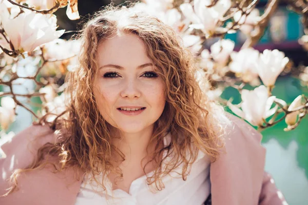 gülümseyen ve kameraya bakarak çiçek açan magnolia, yanındaki parkta poz güzel şık kadın