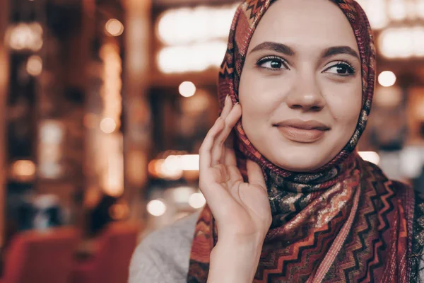 Beautiful young Arab girl with a fashionable headscarf on her head waiting for her food in a restaurant — Stock Photo, Image