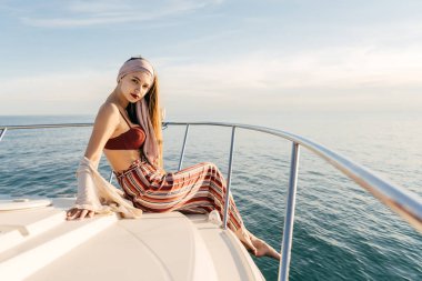 çekici bir şık kız moda yaz pantolon beyaz teknesini aittir, Karayip Denizi ve pozlar yelken