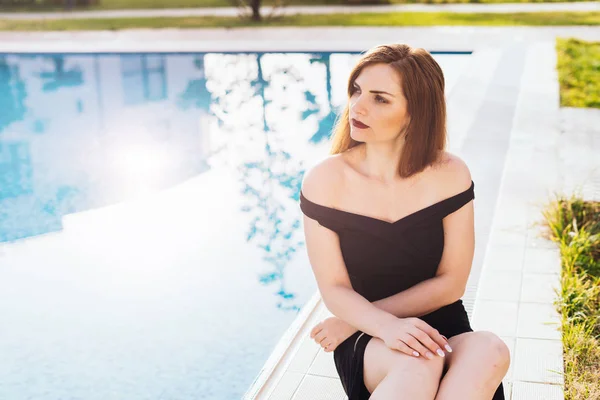 Attractive beautiful girl enjoys relaxing by the blue pool in her garden, a rich life — Stock Photo, Image