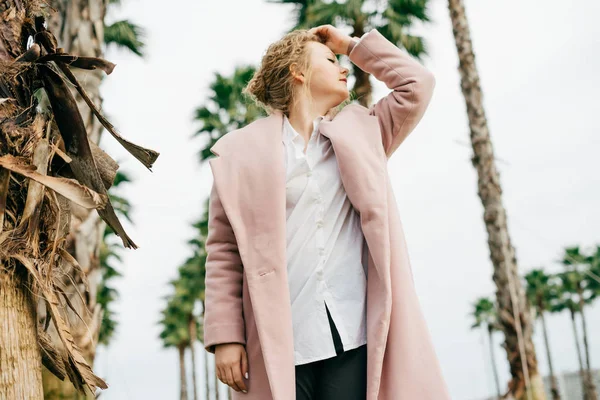 şık şık kız moda pembe paltolu bir fırfır yeşil avuç ile bahar park boyunca yürür