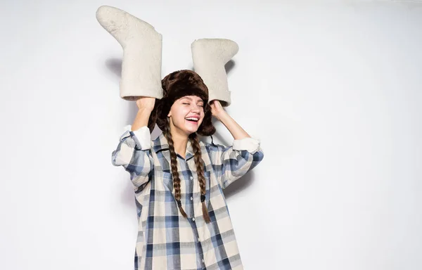 Riéndose chica rusa joven con coletas esperando el invierno, sosteniendo botas de fieltro gris cálido en las manos — Foto de Stock