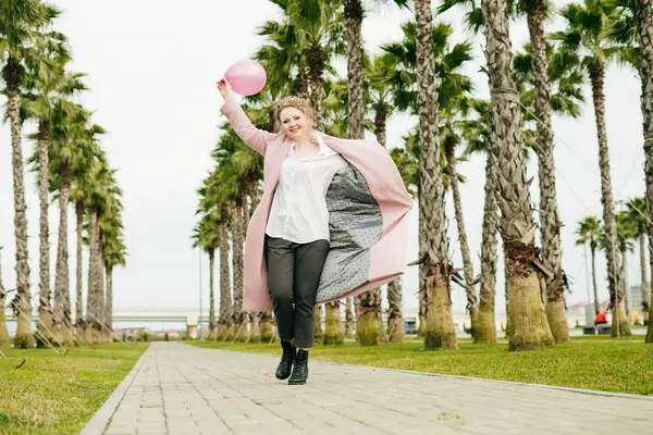 bir bahar Parkı ile yürüme ve gülüyor, bir pembe balon tutan mutlu genç kadın