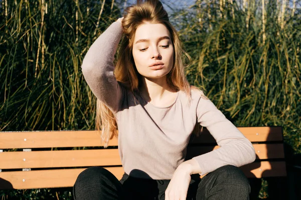çekici kız sarışın model güneşte açık havada, gözleri kapalı bir Bank üzerinde poz