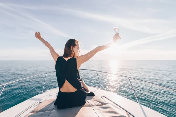 neşeli genç kız beyaz bir teknede oturur, şampanya içiyor ve tatil ve seyahat sahiptir