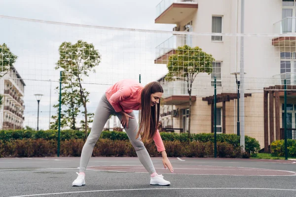 atletik ince kız warmes yukarı ve açık spor alanı üzerinde genişletir