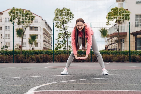 Zeker jonge meisje kneden van spieren voor opleiding op een sportveld, leidt een actieve levensstijl — Stockfoto