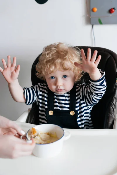 귀여운 파란 눈 곱슬 머리 아이 아이 유용한 수프를 먹고 부엌에 앉아 — 스톡 사진